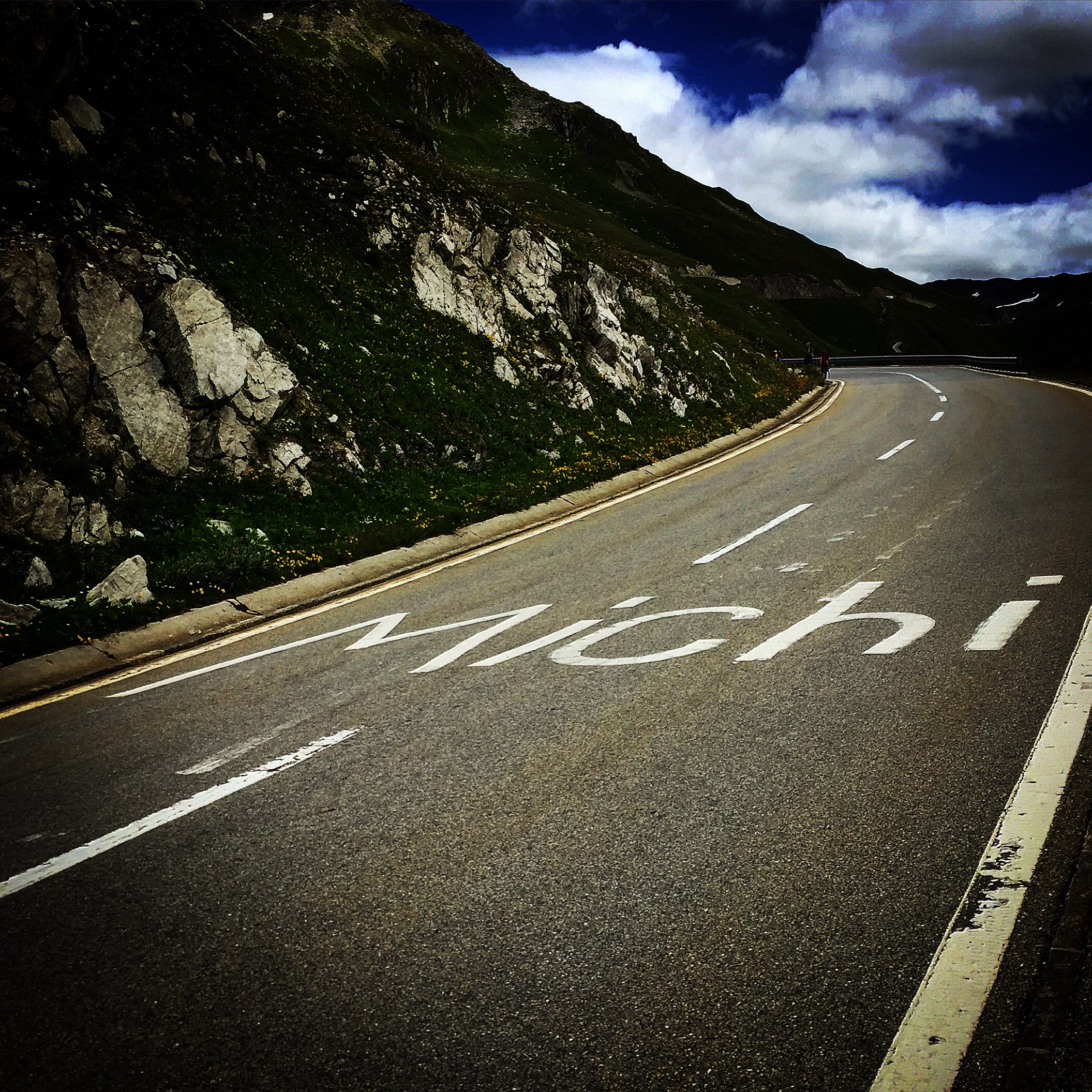 Alpine road with 'Mach!' written on asphalt
